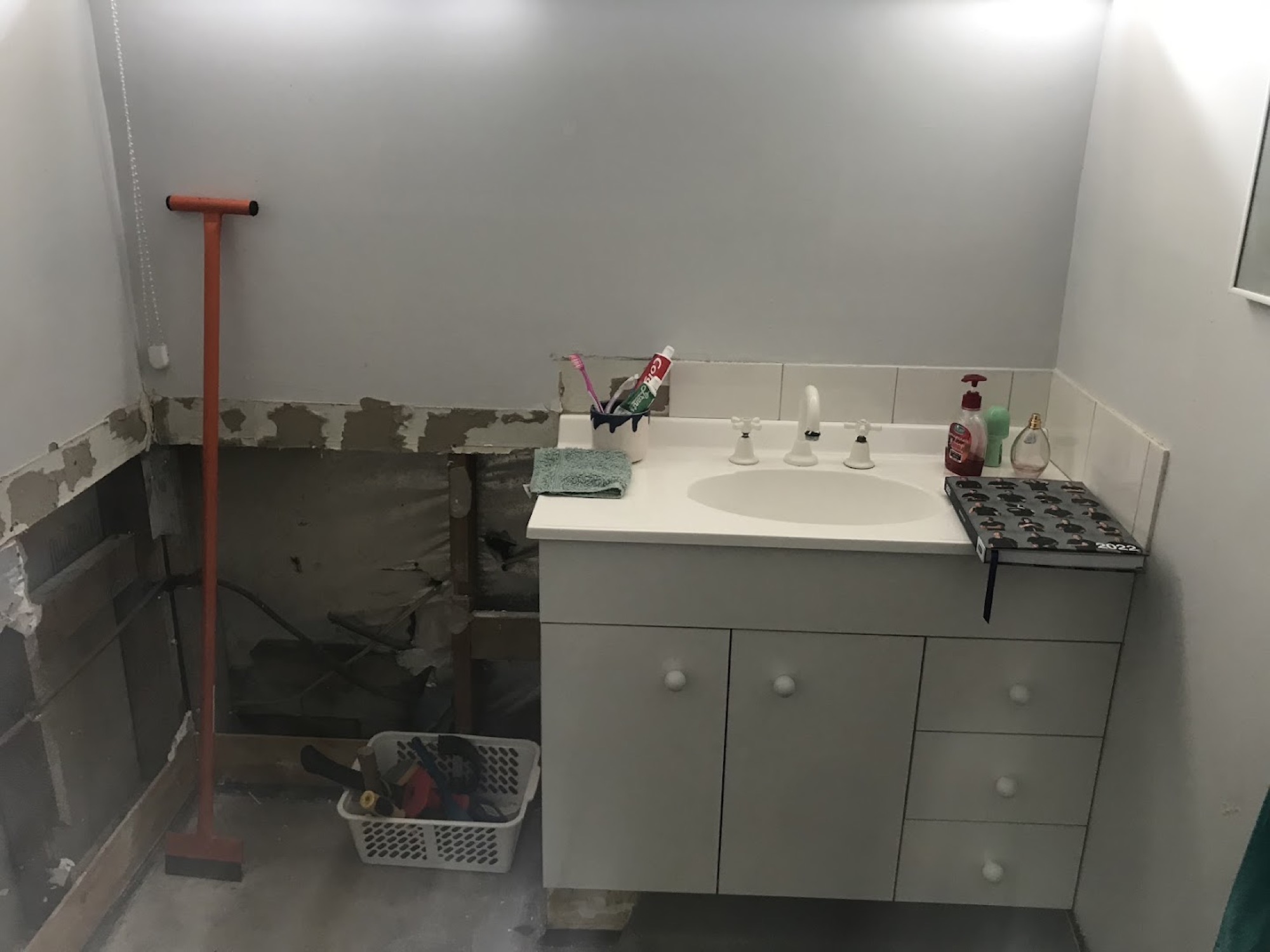 A bathroom stripped back mid-renovation with the wall linings removed around an old vanity