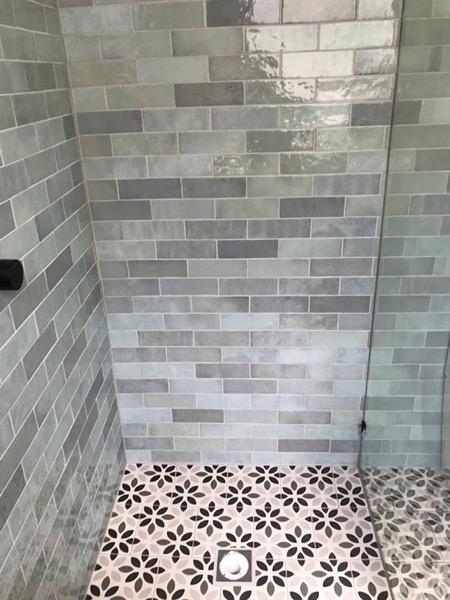 A tiled shower with a centre floor waste and a frameless glass screen