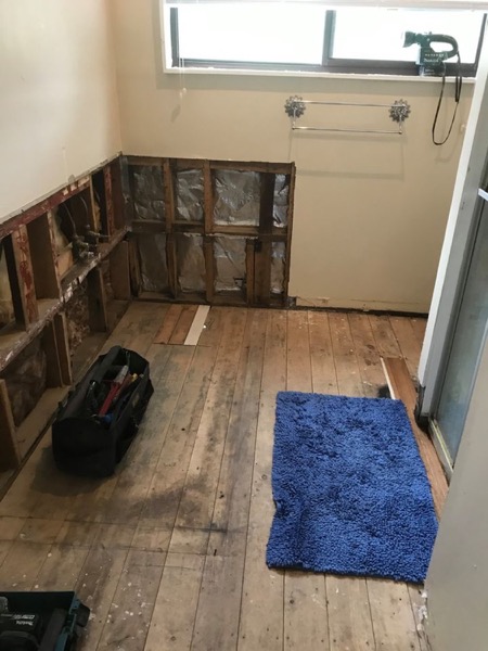 A bathroom stripped back to the floorboards with the wall linings removed