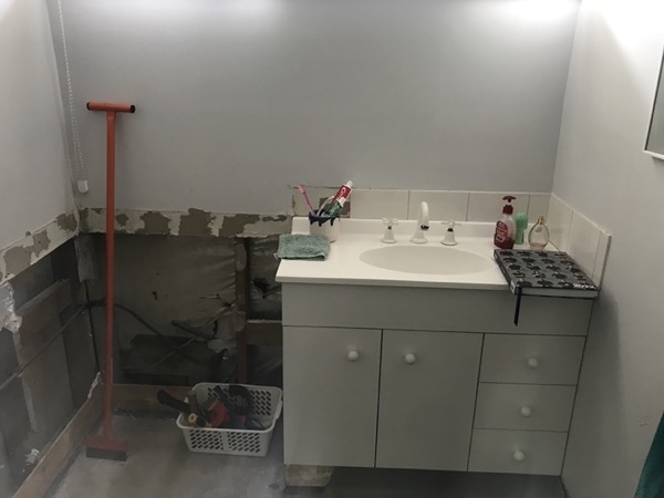 A bathroom stripped back mid-renovation with the wall linings removed around an old vanity