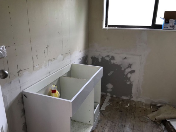 A new vanity carcass standing in a bathroom with the walls stripped back