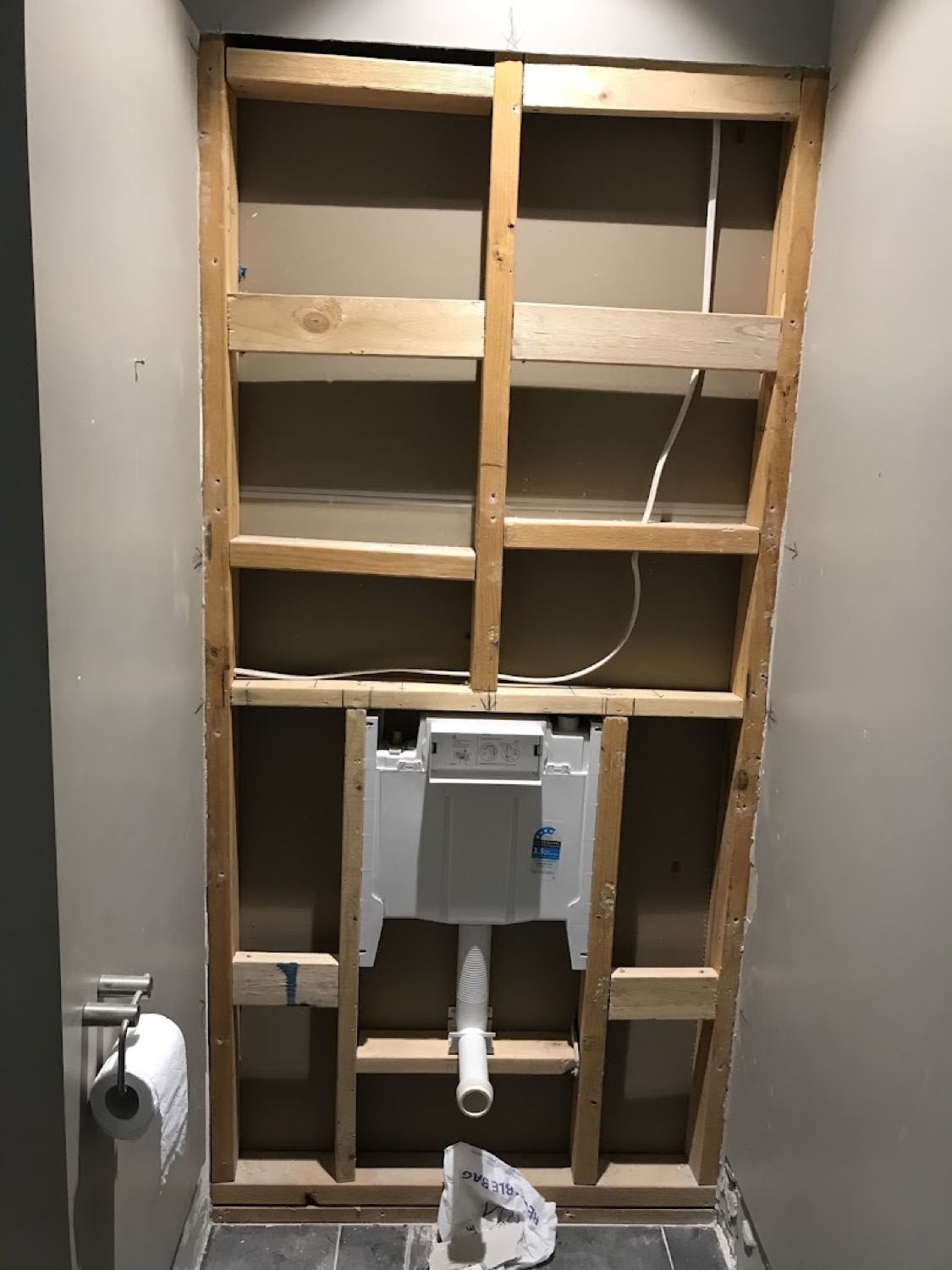 A concealed cistern and waste pipe installed inside an open timber stud wall